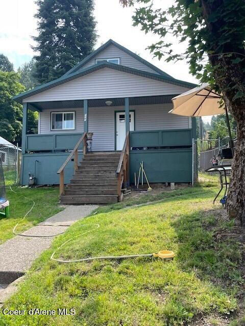 view of front facade with covered porch, fence, stairs, a front lawn, and a trampoline