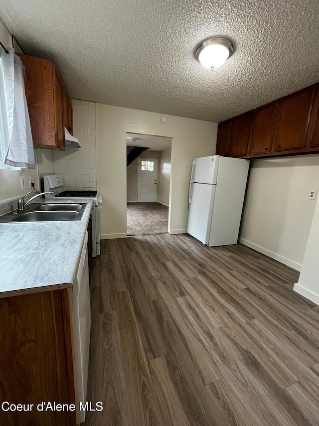 kitchen featuring sink, dark wood-type flooring, a textured ceiling, and white appliances