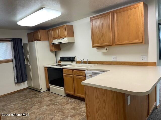 kitchen with exhaust hood, light tile patterned floors, sink, kitchen peninsula, and white appliances