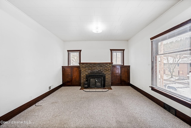 carpeted living room with a healthy amount of sunlight, a wood stove, and crown molding