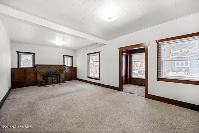 unfurnished living room featuring light carpet, a brick fireplace, and a wealth of natural light