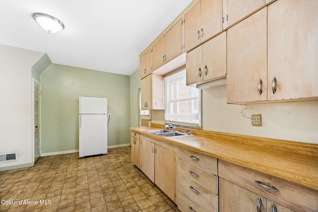 kitchen featuring sink, light brown cabinets, and white refrigerator