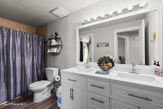 bathroom with wood-type flooring, a textured ceiling, vanity, toilet, and walk in shower