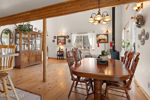 dining space featuring light wood finished floors, beam ceiling, and an inviting chandelier