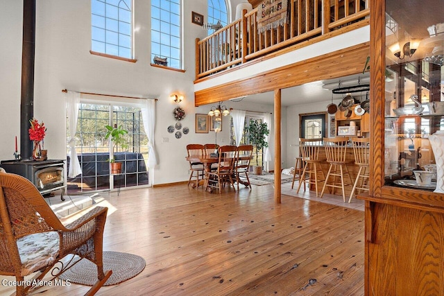 living room with a towering ceiling, a wood stove, and wood-type flooring