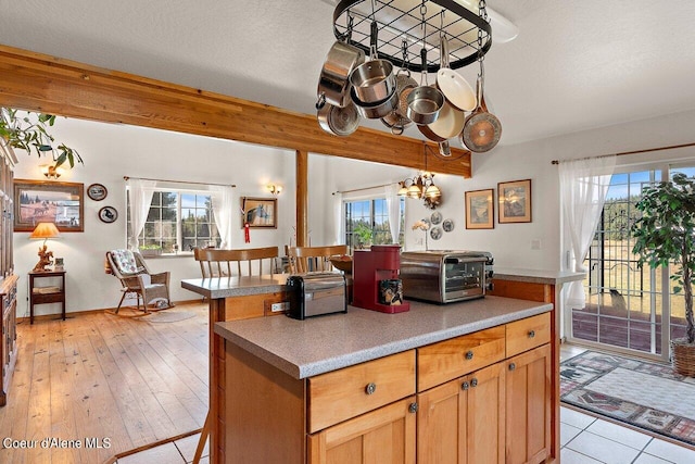 kitchen with a kitchen bar, light wood-type flooring, a chandelier, a textured ceiling, and hanging light fixtures