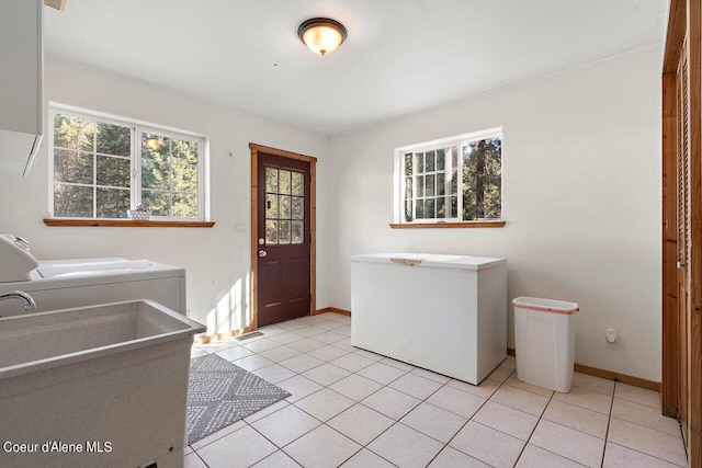 washroom with washer and clothes dryer, laundry area, baseboards, and light tile patterned floors