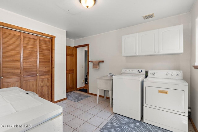 laundry area featuring washer and dryer, cabinets, and light tile patterned floors