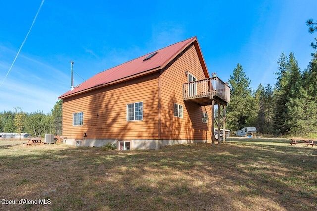 view of home's exterior with a balcony, central AC, and a lawn