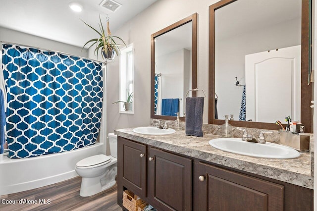 full bathroom featuring hardwood / wood-style floors, toilet, shower / bathtub combination with curtain, and vanity