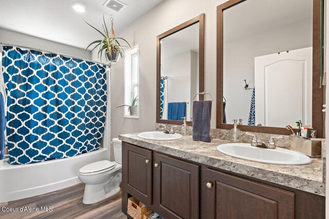 bathroom with a sink, visible vents, wood finished floors, and double vanity