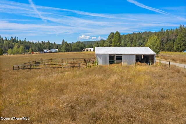 exterior space with an outbuilding, fence, a forest view, a rural view, and a pole building