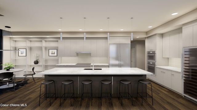 kitchen with a large island with sink, stainless steel appliances, a kitchen breakfast bar, modern cabinets, and tasteful backsplash