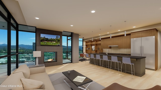 living area with light wood-type flooring, expansive windows, recessed lighting, and a tiled fireplace