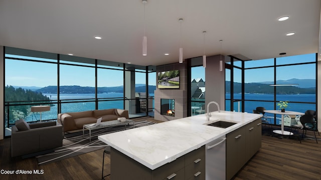 kitchen featuring a wall of windows, an island with sink, a fireplace, a sink, and modern cabinets