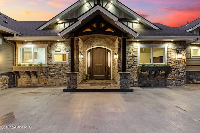 8491 N Mckinley Ln, Hayden, ID 83835 - exterior entry at dusk featuring stone siding and a shingled roof