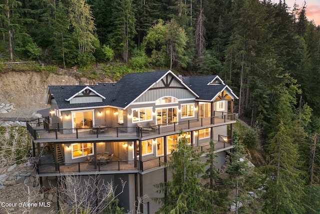 8491 N Mckinley Ln, Hayden, ID 83835 - rear view of property with a balcony, board and batten siding, a shingled roof, and a forest view