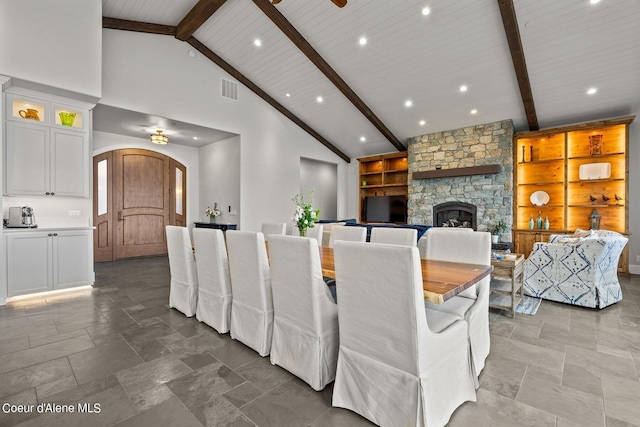 8491 N Mckinley Ln, Hayden, ID 83835 - dining room with stone finish floor, high vaulted ceiling, arched walkways, beamed ceiling, and a stone fireplace