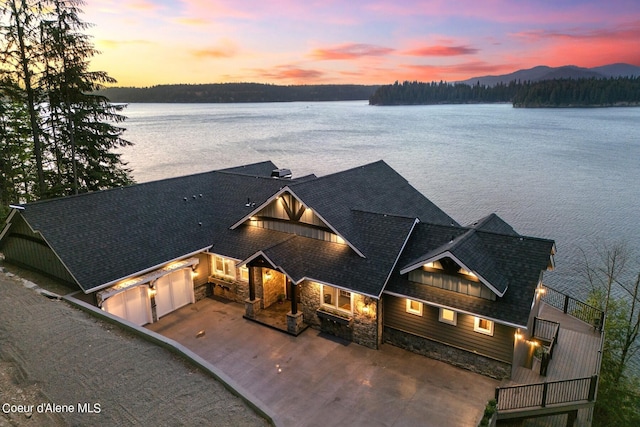 8491 N Mckinley Ln, Hayden, ID 83835 - view of front of home featuring stone siding, a water view, driveway, and an attached garage