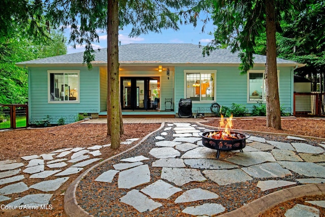 rear view of property with a wooden deck, a patio, and a fire pit