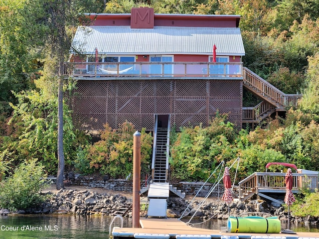 back of property with a deck with water view, metal roof, and stairs