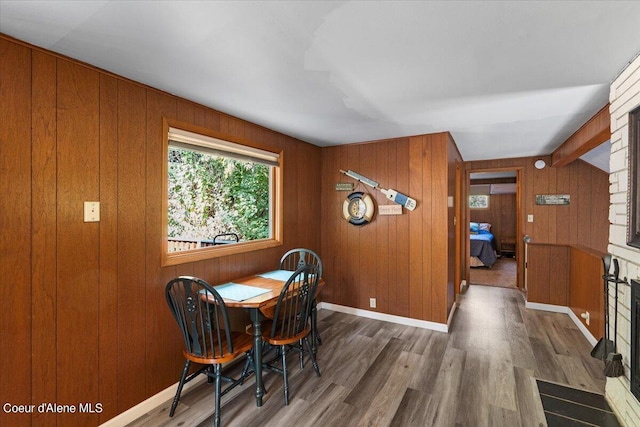 dining room featuring lofted ceiling, wood walls, wood finished floors, and baseboards