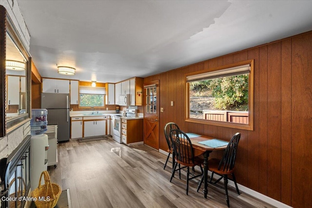 kitchen with white range with electric stovetop, light countertops, light wood-style floors, freestanding refrigerator, and a sink