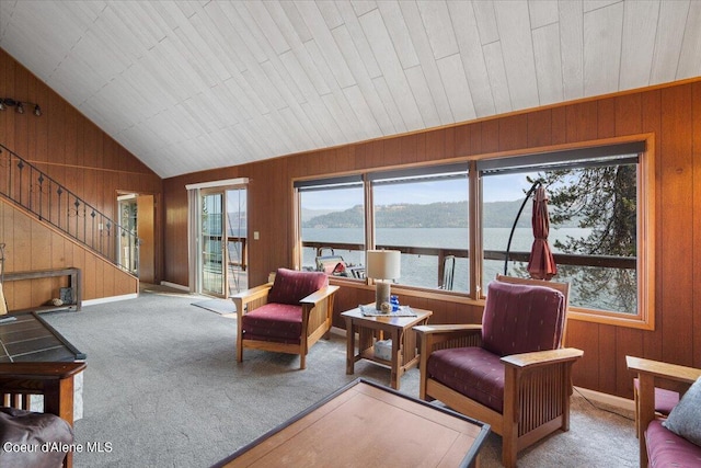 living area with wood walls, stairs, and vaulted ceiling