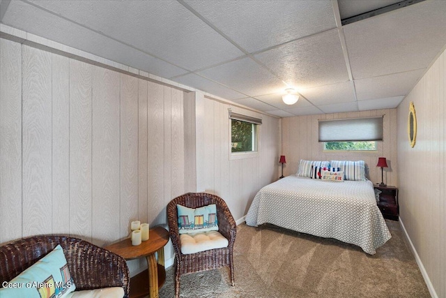 bedroom featuring wood walls, multiple windows, carpet flooring, and a paneled ceiling