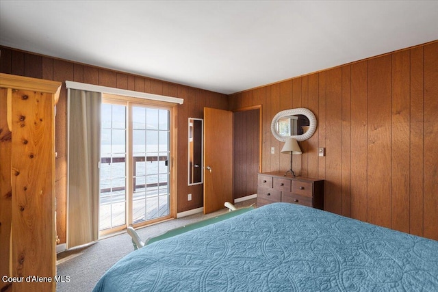 carpeted bedroom featuring access to outside and wood walls