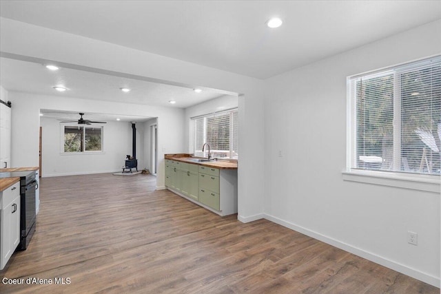 kitchen with wood-type flooring, butcher block counters, sink, and a wealth of natural light