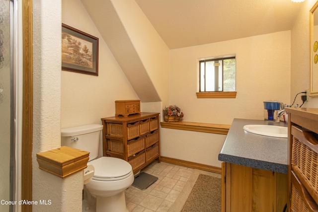 bathroom featuring vanity, toilet, and lofted ceiling