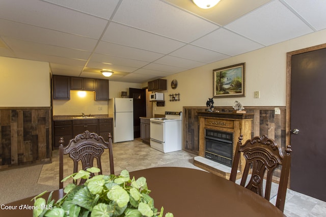 dining room featuring a drop ceiling, wooden walls, and sink