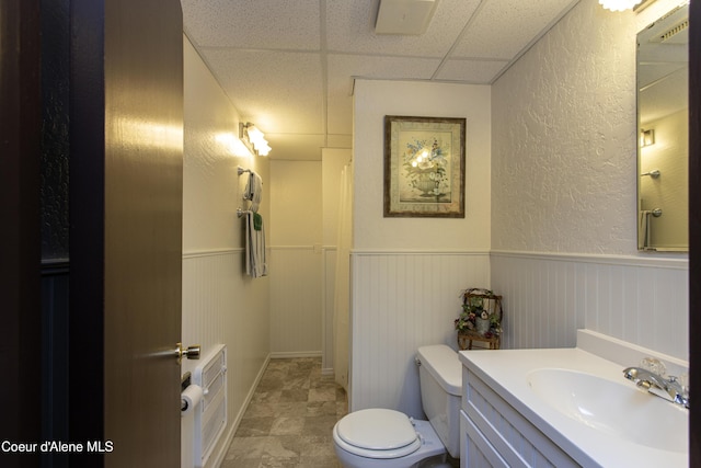 bathroom with a paneled ceiling, vanity, and toilet