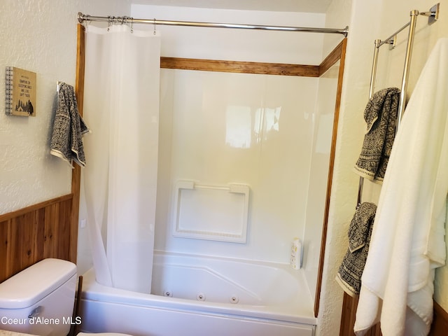 bathroom with wooden walls, shower / bath combination with curtain, and toilet