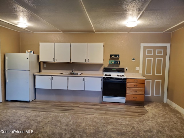 kitchen with white cabinets, white appliances, sink, and light carpet