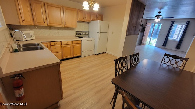 kitchen featuring ceiling fan with notable chandelier, light wood-type flooring, white appliances, and hanging light fixtures