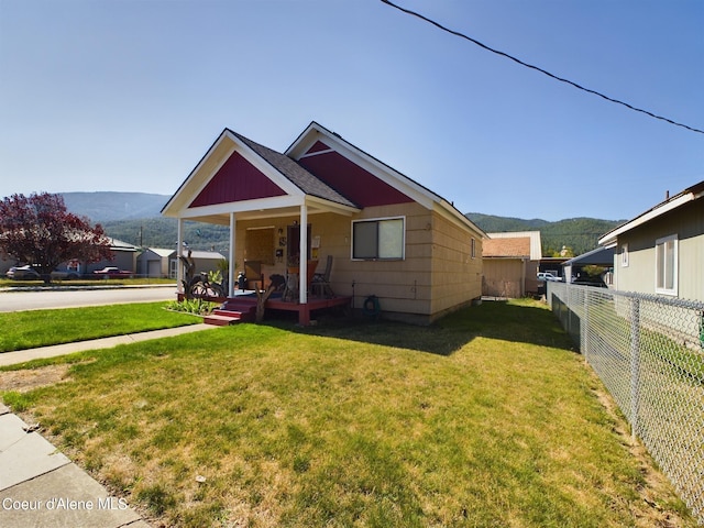 view of front facade with a mountain view, covered porch, and a front yard