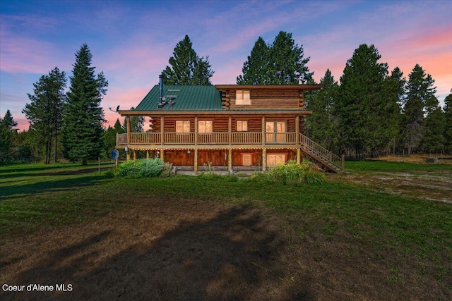 back house at dusk featuring a wooden deck and a lawn