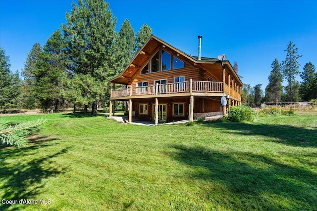 rear view of property with a yard, a wooden deck, and a patio