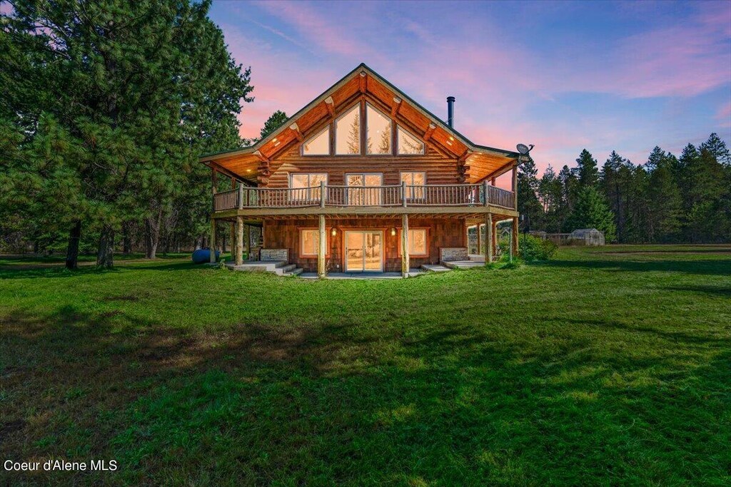 back house at dusk featuring a yard, a wooden deck, and a patio