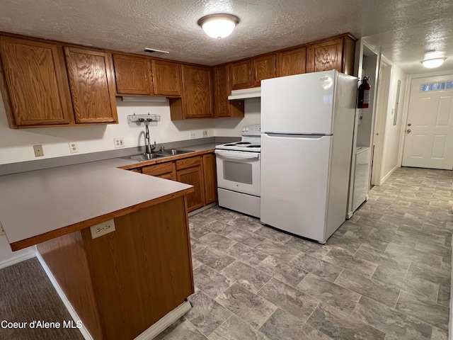 kitchen featuring a textured ceiling, kitchen peninsula, white appliances, and sink