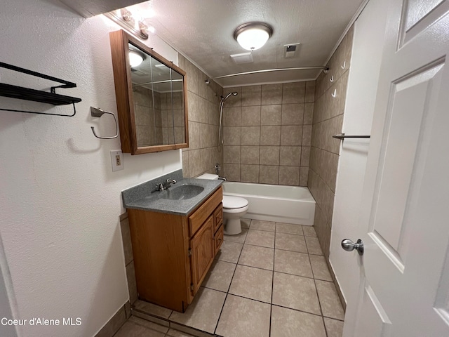 full bathroom featuring vanity, tile patterned flooring, tiled shower / bath combo, toilet, and a textured ceiling