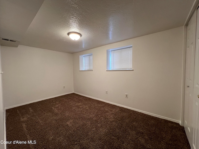 basement with dark carpet and a textured ceiling