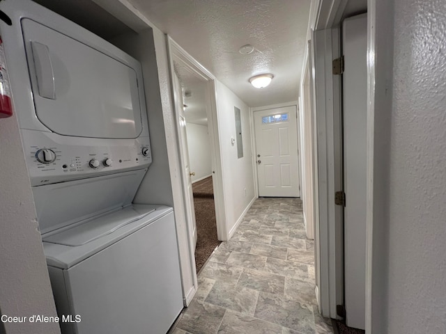 washroom with stacked washing maching and dryer and a textured ceiling