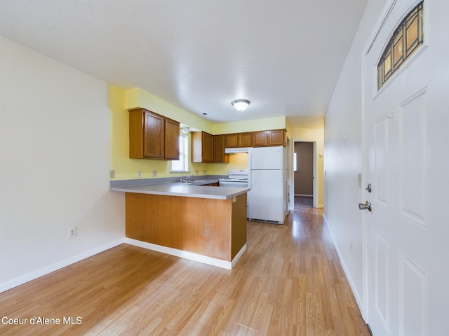 kitchen featuring light hardwood / wood-style floors, sink, white appliances, and kitchen peninsula