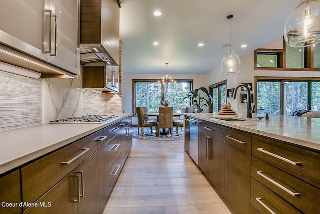 L3B10 N Walden Loop, Rathdrum, ID 83858 - kitchen featuring appliances with stainless steel finishes, decorative backsplash, light hardwood / wood-style floors, pendant lighting, and sink