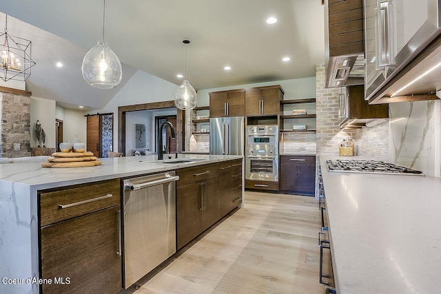L3B10 N Walden Loop, Rathdrum, ID 83858 - kitchen featuring hanging light fixtures, sink, tasteful backsplash, dark brown cabinets, and a large island with sink