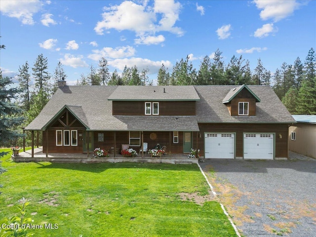 view of front of home featuring a porch, a garage, and a front lawn