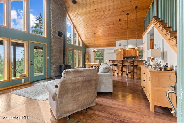 living room featuring a wealth of natural light, dark wood-type flooring, an AC wall unit, and high vaulted ceiling